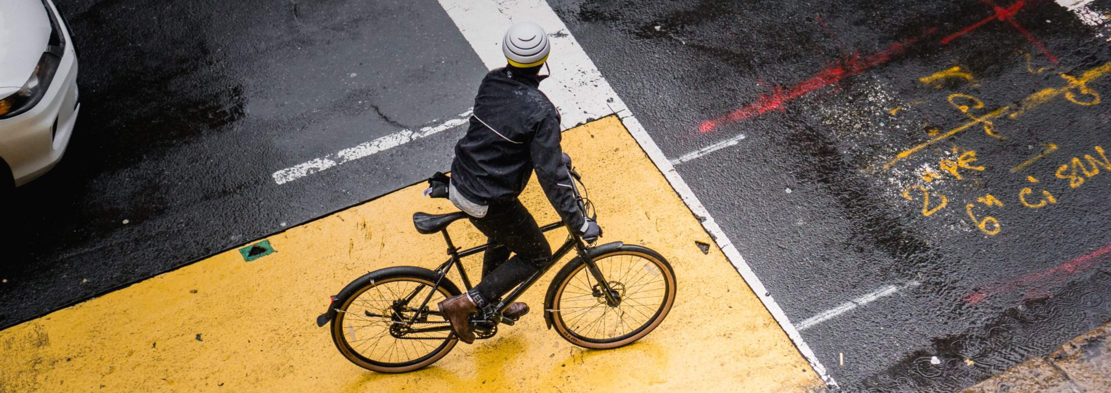 Person riding a bike across a wet city intersection.