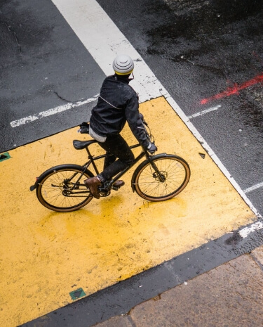 Person riding a bike across a wet city intersection.